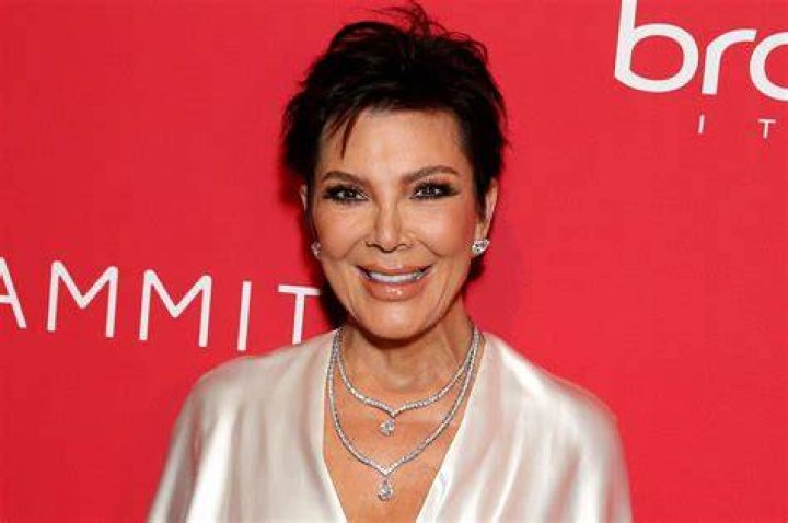 Kris Jenner smiling with snakeskin gloves